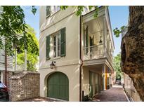 Charming home exterior with green shutters, covered balcony, and brick paved walkway with arched garage at 4 Catfiddle St, Charleston, SC 29403