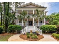 Charming two-story home with a columned front porch, manicured landscaping, and an American flag at 4991 Sound View Dr, Mount Pleasant, SC 29466