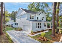 Charming two-story home features light blue siding, an attached garage, and a well-manicured front yard with mature trees at 5655 Captain Kidd Rd, Hollywood, SC 29449