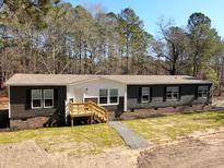 Charming single-story home with dark siding and a welcoming front porch entrance at 945 Tiger Loop, Saint Stephen, SC 29479