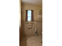 Neutral tiled bathroom with window, decorative towel, and toilet paper holder at 107 Kelly St, Walterboro, SC 29488