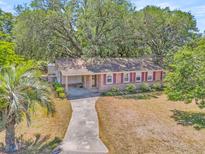Charming single-story home with brick facade, red shutters, and a driveway leading to a covered porch at 1143 Winborn Dr, Charleston, SC 29412