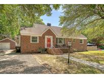 Charming brick home with a red front door, walkway, and lush green trees on a sunny day at 13 Charlestowne Rd Rd, Charleston, SC 29407