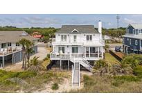 Charming raised beach house featuring a large deck, fenced yard, and private beach access at 1404 Palmetto Blvd, Edisto Beach, SC 29438