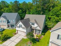 Well-manicured lawn and inviting front porch create a warm welcome to this home with an attached two-car garage at 204 Black Gum Cir, Moncks Corner, SC 29461