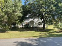 Traditional two-story home with a covered porch and mature trees, set on a spacious lawn at 217 Scotia St, McClellanville, SC 29458