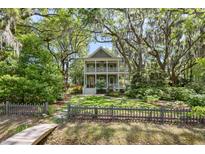 Inviting two-story home with double porches, lush landscaping, and mature trees with Spanish moss at 2187 Saint James Dr, Charleston, SC 29412