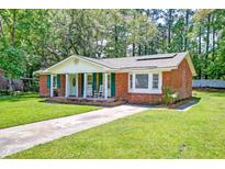 Charming brick home featuring a well-manicured lawn, inviting front porch, and vibrant green shutters at 403 Forest Cir, Summerville, SC 29483
