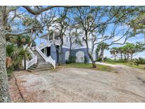 Charming beach house with a light-colored exterior, tall staircase, and lovely mature trees at 67 Lost Village Trl # 4, Edisto Island, SC 29438