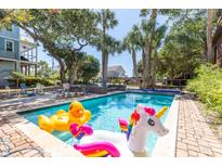 Refreshing backyard pool with fun inflatables, surrounded by a brick patio and lush greenery at 220 E Arctic Ave, Folly Beach, SC 29439