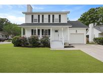 Charming two-story home featuring white siding, black shutters, a well-manicured lawn, and an attached garage at 4301 Trevor St, North Charleston, SC 29420