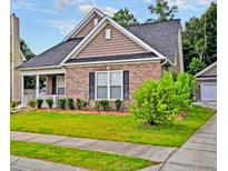 Charming single-Gathering home featuring a brick facade, well-manicured lawn, and a detached garage at 136 Pavilion St, Summerville, SC 29483