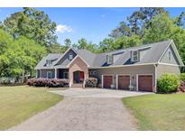 Charming home featuring gray siding, a brick entrance, a three car garage, and lush landscaping at 225 Ridge Rd, Ridgeville, SC 29472
