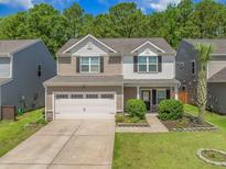 Charming two-story home with a two-car garage, manicured lawn, and delightful landscaping at 259 Weeping Cypress Dr, Moncks Corner, SC 29461