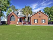 Charming brick home with a well-manicured lawn and a classic front porch, enhancing its curb appeal at 5505 Indigo Makers Trce, Charleston, SC 29418