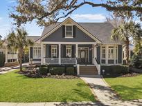 Charming blue two-story home featuring a welcoming front porch and lush, landscaped yard at 127 Beresford Creek St, Daniel Island, SC 29492