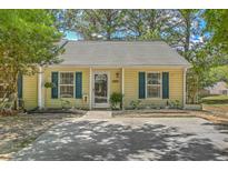 Charming one-story home featuring yellow siding, blue shutters, and a well-manicured lawn with mature trees at 1507 Blaze Ln, Charleston, SC 29412