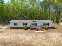 Charming single-story home featuring a cozy front porch and complemented by a lush green backdrop of mature trees at 120 Perry Hill Rd, Moncks Corner, SC 29461