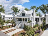 Stunning two-story white home featuring a charming porch, white metal roof and lush landscaping at 2229 Boatwright Rd, Johns Island, SC 29455