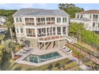 Stunning three-story home with private pool, outdoor lounge, and picturesque fenced-in yard at 3128 Palmetto Blvd, Edisto Island, SC 29438