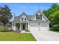 Charming two-story home featuring a well-manicured lawn, attached two car garage, and welcoming front porch at 402 Bay Creek Dr, Charleston, SC 29414