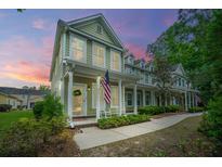 Charming two-story house featuring a welcoming front porch with an American flag at sunset at 78 Branch Creek Trl, Summerville, SC 29483