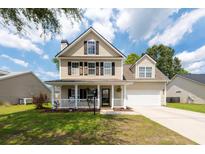 Charming two-story home featuring a covered front porch, well-maintained lawn, and attached two-car garage at 139 Spindle Way, Goose Creek, SC 29445