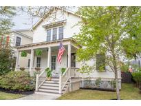 Charming two-story home with a welcoming front porch, American flag, and manicured landscaping at 1445 Lettered Olive Ln, Mount Pleasant, SC 29464