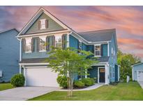 Charming two-story home with blue siding, well-manicured lawn, and attached two-car garage at 2324 Town Woods Rd, Charleston, SC 29414