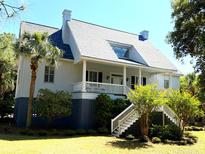 Charming home with a wide porch, manicured lawn, and lush landscaping creating an inviting curb appeal at 2624 Jenkins Point Rd, Seabrook Island, SC 29455