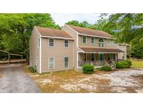 Charming two-story home featuring a covered front porch and lush surroundings at 312 Piney Grove Rd, Cross, SC 29436
