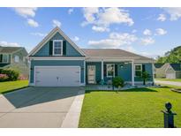 Charming blue home with a well-manicured lawn and a two-car garage on a sunny day at 3801 Canary Ct, North Charleston, SC 29420