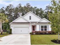 Charming one-story home featuring a well-manicured lawn, white exterior, and a bright pink front door at 512 Pontoon Rd, Huger, SC 29450