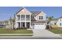 Charming two-story home featuring a welcoming front porch, two car garage and freshly manicured lawn at 661 Black Pine Rd, Moncks Corner, SC 29461