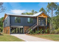 Stunning exterior view of a modern home featuring a metal roof, wooden accents, and lush landscaping at 1014 E Erie Ave, Folly Beach, SC 29439