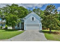 Charming light blue home featuring a well-manicured lawn, mature trees, and a two-car garage at 106 Trimley Ct, Goose Creek, SC 29445