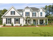 Charming two-story white farmhouse-style home with well-manicured lawn and landscaping at 1411 Homecoming Blvd, Ravenel, SC 29470