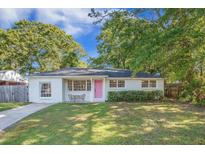 Charming white brick home with a well-manicured lawn and a bright pink front door at 2010 Culver Ave, Charleston, SC 29407