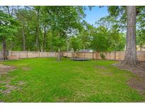 Spacious fenced backyard with lush green grass and mature trees, perfect for outdoor activities at 2436 Stingray Blvd, North Charleston, SC 29406