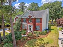 A stunning aerial view of a red brick home, manicured lawn, mature trees, and picturesque landscaping at 322 Clubview Rd, Summerville, SC 29485