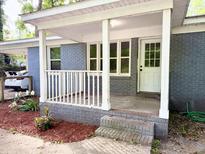 Charming front porch with white columns and railing, complemented by brick steps and vibrant flowerbeds at 354 Deloach Ave, Walterboro, SC 29488