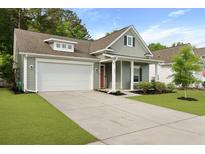 Charming single-Gathering home featuring a two-car garage, gray siding, orange door, and well-maintained landscaping at 1221 Lois Allen Rd, Johns Island, SC 29455