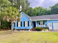Charming blue home with a manicured front yard and a mature palm tree, showcasing curb appeal at 1325 Edward Dr, Moncks Corner, SC 29461