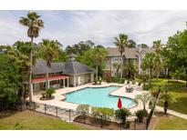 A serene community pool area with palm trees, lounge chairs, and umbrellas offers a relaxing outdoor experience at 188 Midland Parkway # 110, Summerville, SC 29485