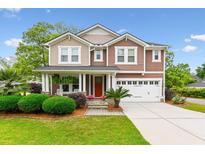 Beautiful two-story home featuring well-manicured lawn, red door, and attached two-car garage at 2017 Woodland Shores Rd, Charleston, SC 29412