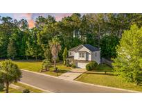 Inviting two-story home featuring a well-manicured lawn and a long driveway leading to an attached garage at 240 Woodbrook Way, Moncks Corner, SC 29461