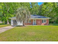 Charming brick home with a lush green lawn and a mature palm tree in the front yard at 2736 Shadow Ln, North Charleston, SC 29406