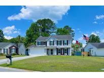 Traditional two-story home featuring a manicured lawn, attached garage, and charming curb appeal under a blue sky at 302 Axeminster Ct, Goose Creek, SC 29445