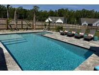 Sparkling blue swimming pool with lounge chairs and lush landscaping in a private backyard setting at 3173 Hugh Bennett Dr, Johns Island, SC 29455