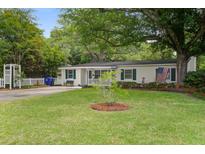 Charming single-story home featuring a lush green lawn, mature trees, and a quaint front porch at 344 Lantana Dr, Charleston, SC 29407